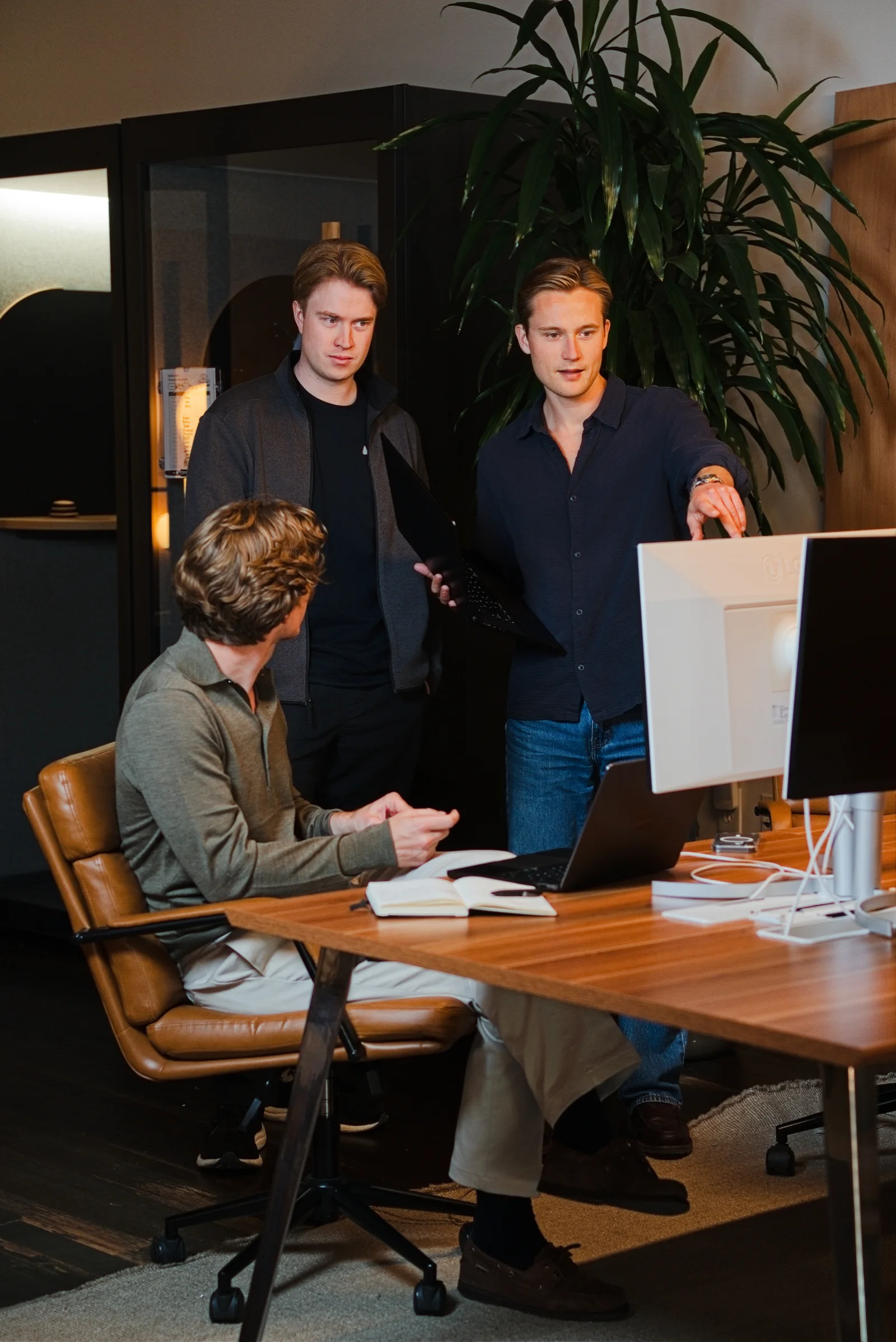 Three Audun colleagues reviewing work on a monitor together.