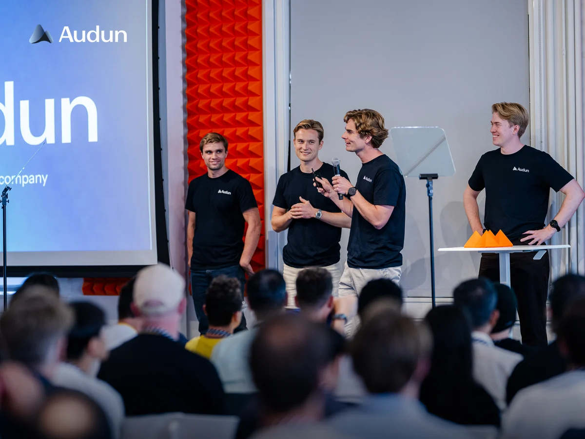 Four Audun team members presenting on stage in front of an audience.